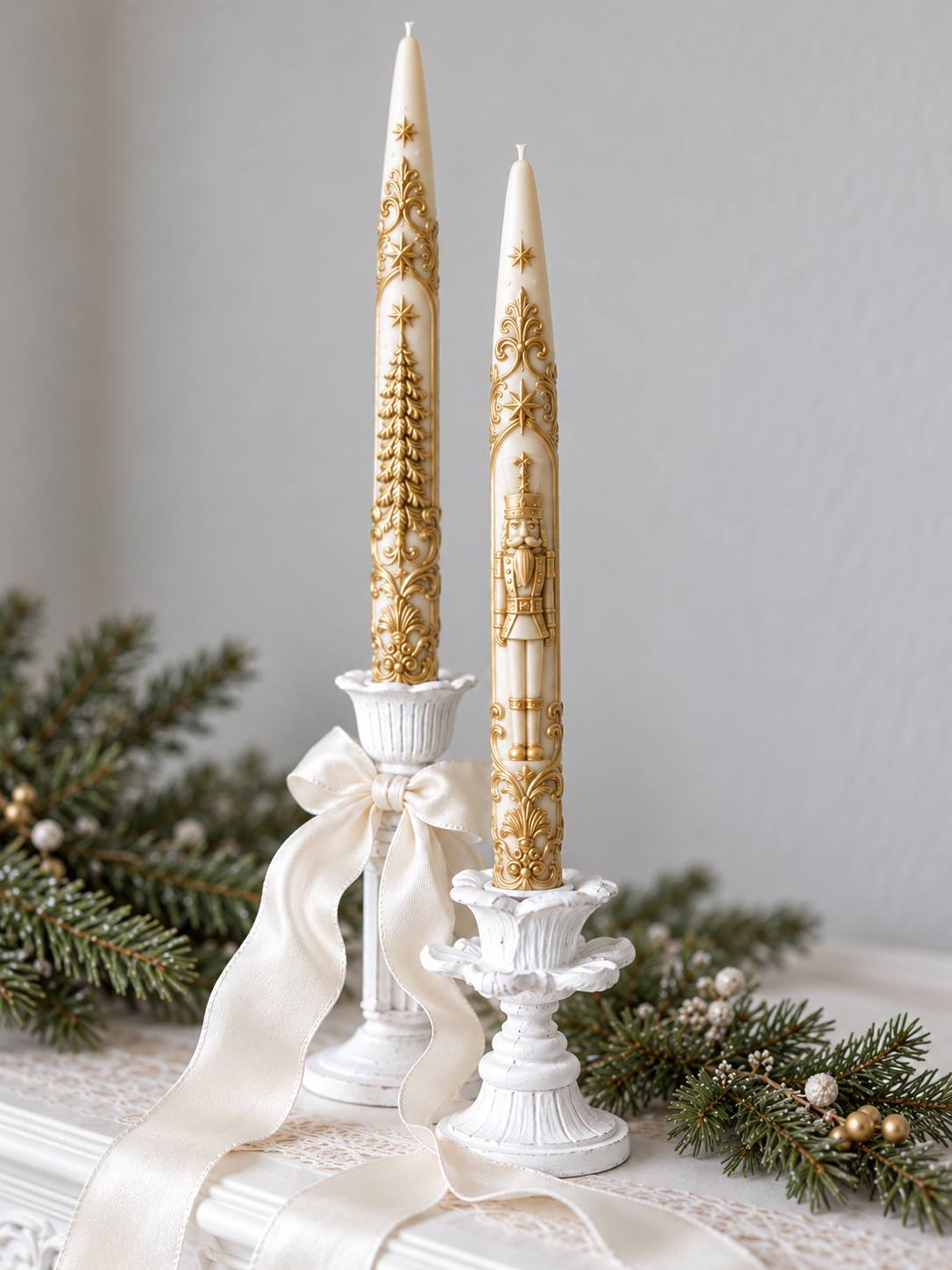 Pair of ivory Nutcracker Style taper candles with gold nutcracker soldier and Christmas tree relief in white candlesticks with a satin ribbon