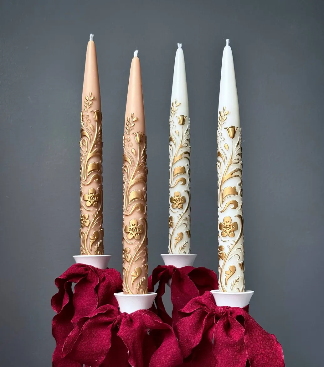 Gold ornate taper candles with red ribbon
